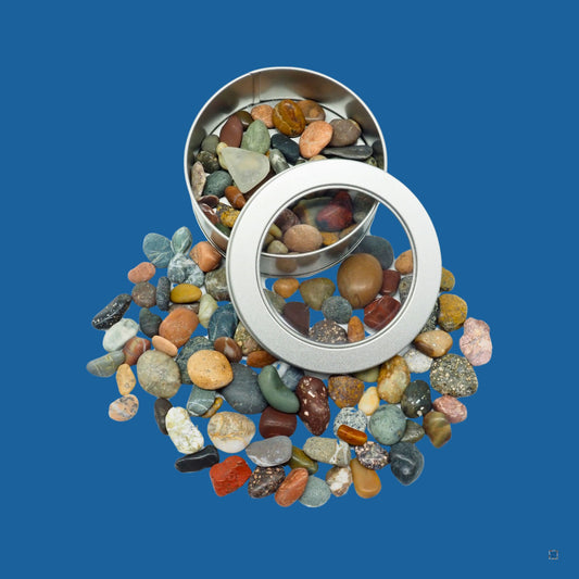 Colorful sea pebbles spilling from metal tin with clear lid